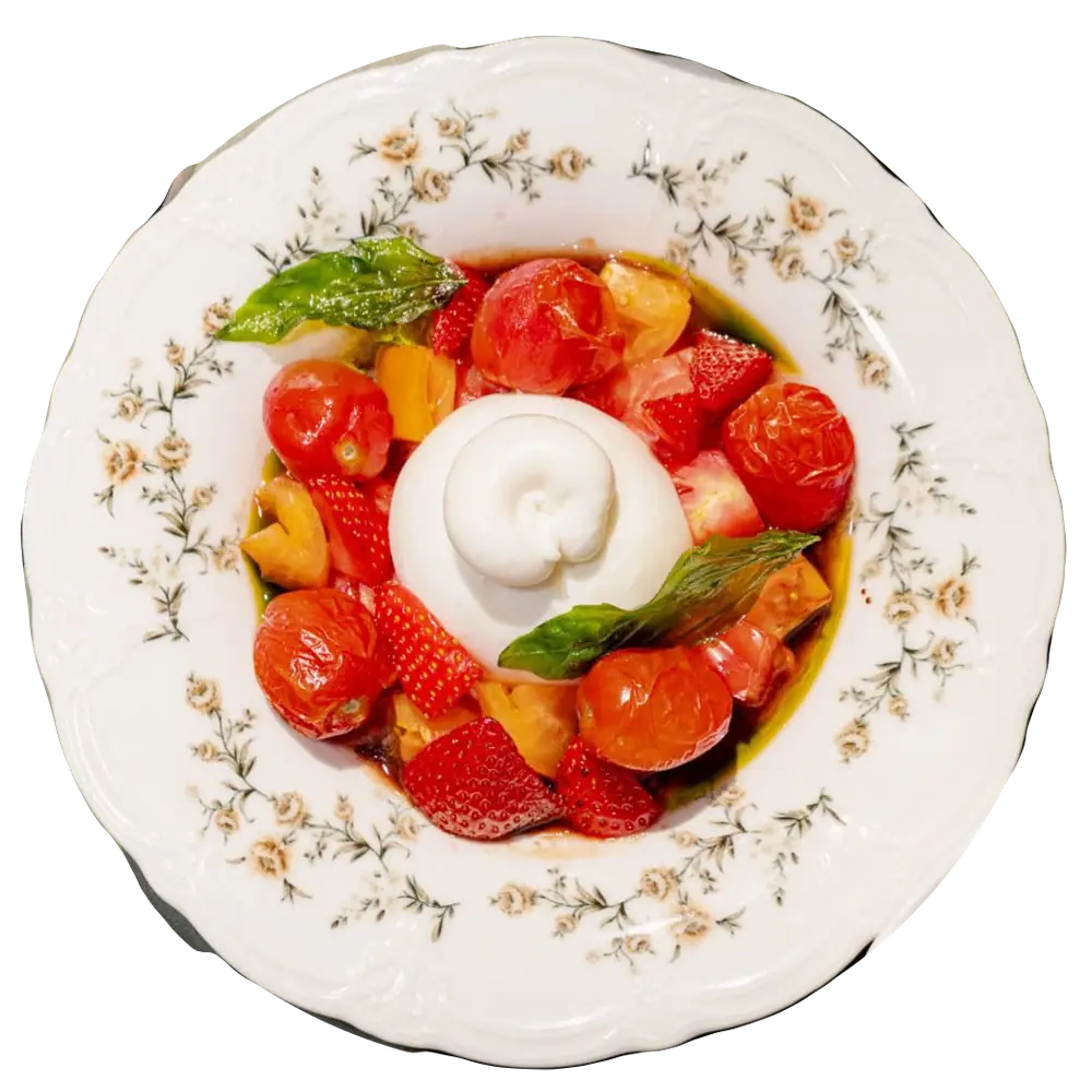 Burrata w gazpacho z pomidorami i truskawkami na talerzu w kwiaty